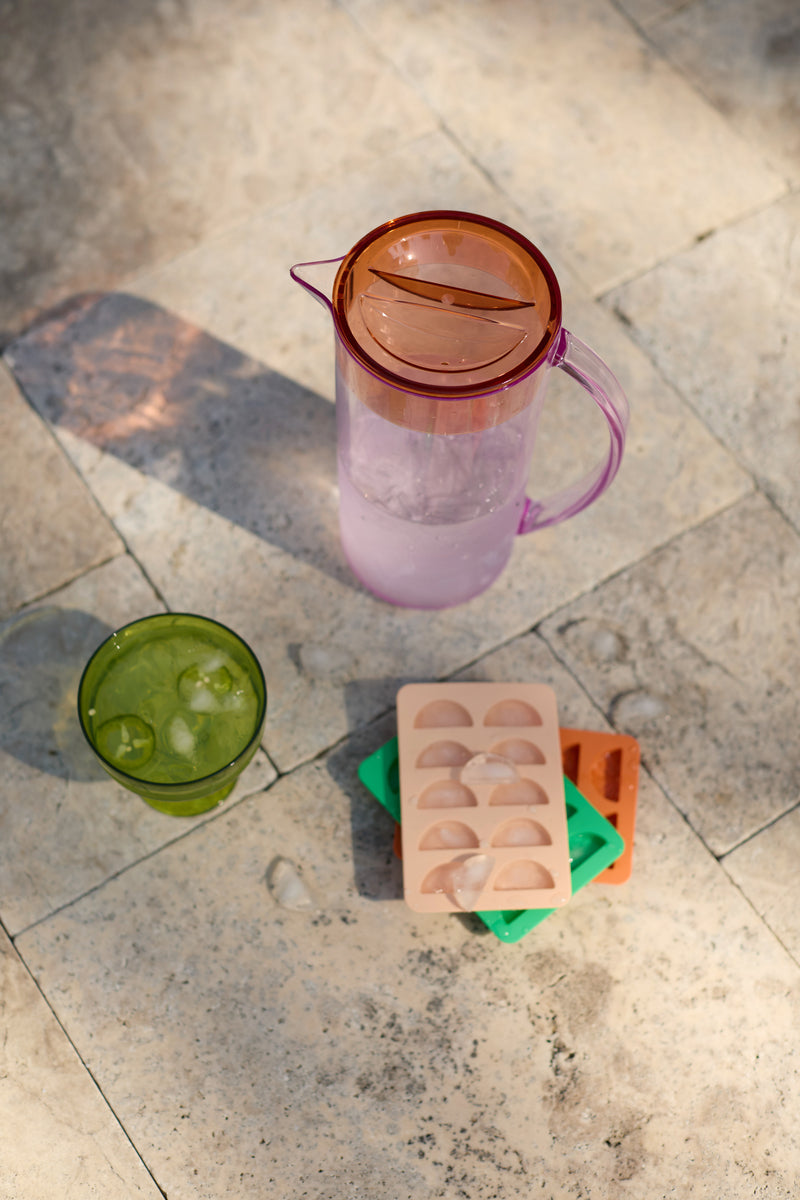 A pitcher of water, a green glass with ice cubes, and The Dotty Citrus Wedge Ice Trays add a playful touch to the sunlit tiled surface.