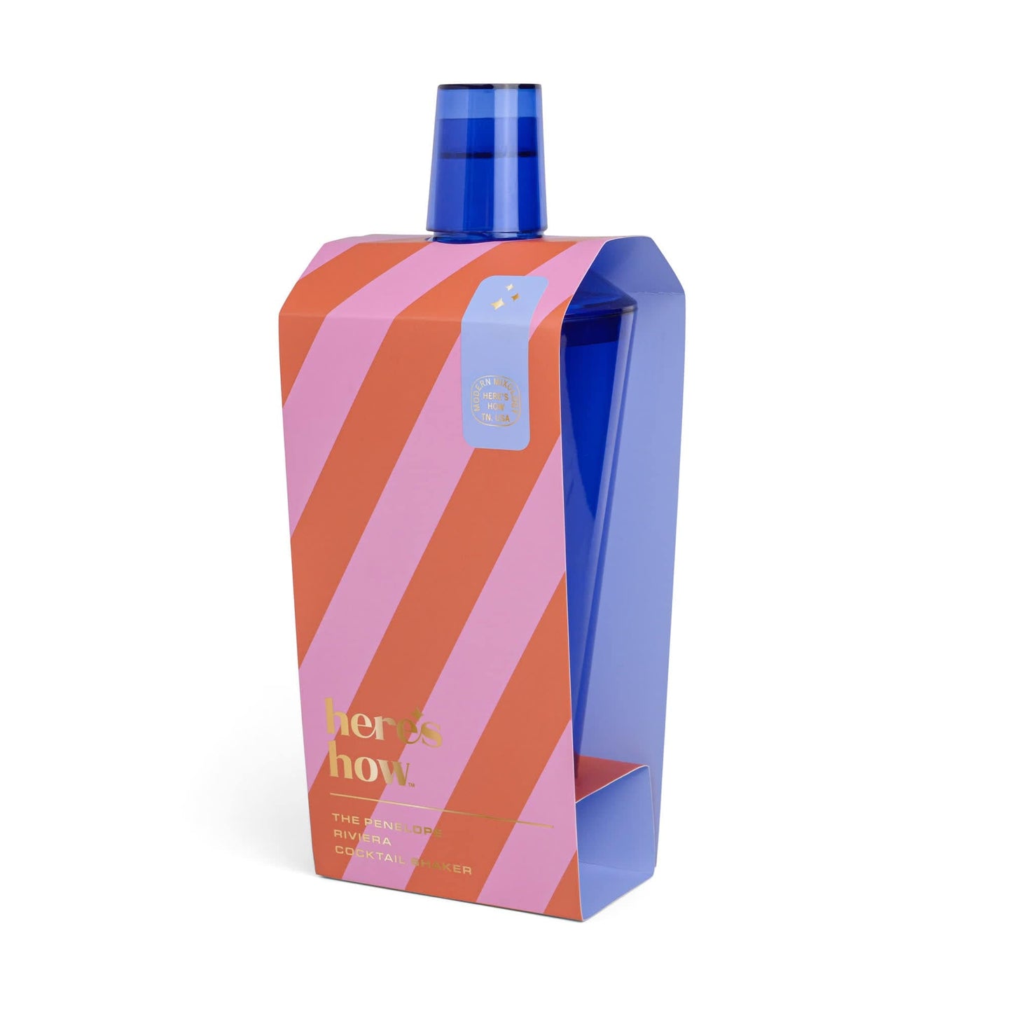The Penelope Cocktail Shaker features a blue bottle with a matching cap, partially wrapped in a pink and red striped sleeve with gold “here’s how” text—ideal for al fresco entertaining.