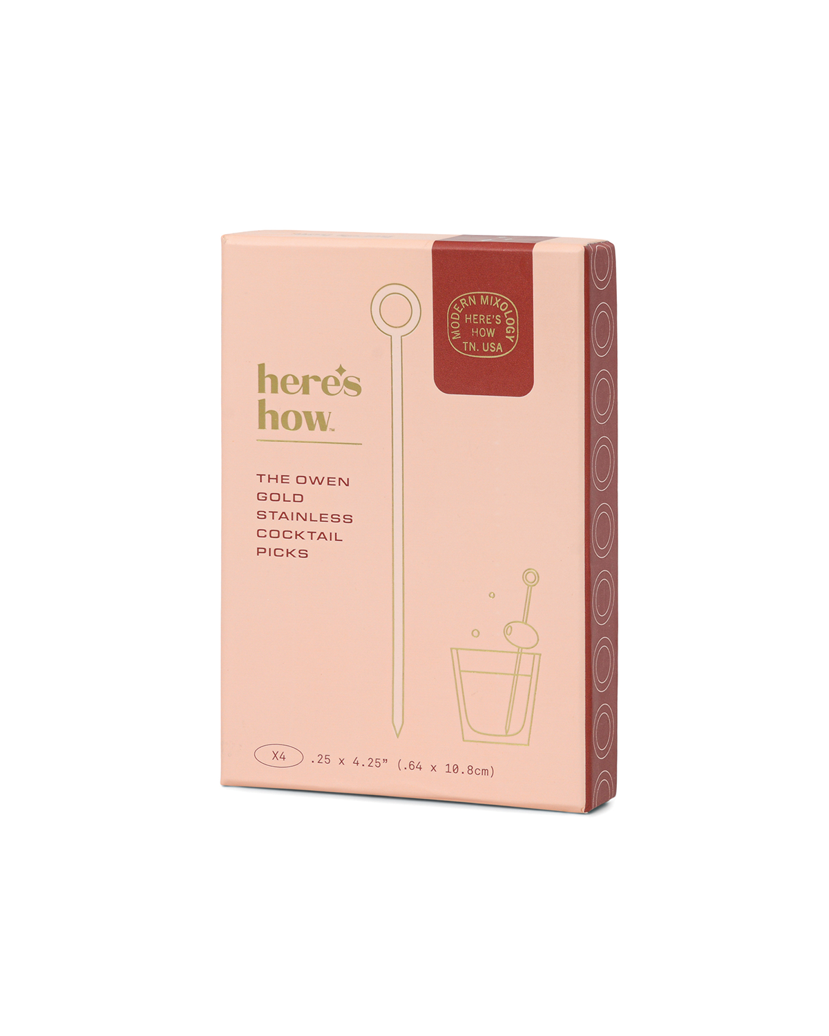 A pink and red box labeled “here’s how. The Owen,” featuring gold plated cocktail picks and an illustration of a cocktail glass on the front.