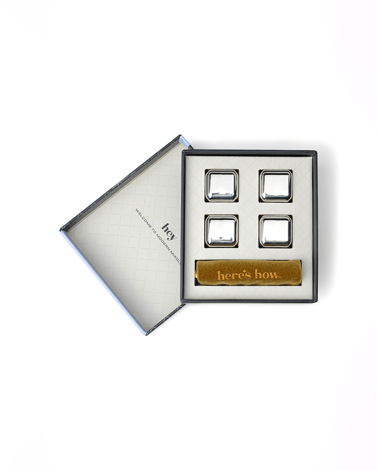 Open box containing four Ruby Cubes—stainless-steel, freezable chillers that keep drinks cold without dilution—and a gold rectangular “here’s how…” card, all arranged neatly inside.