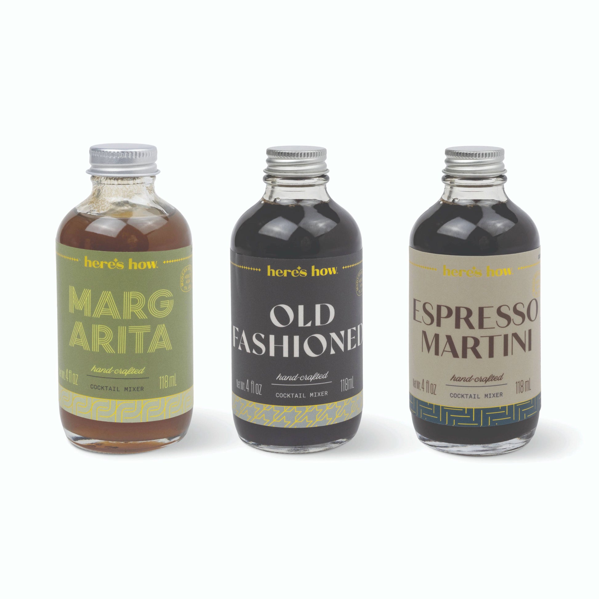 Three small glass cocktail mix bottles with silver caps on a white background: 'here's how' Marg Arita, Old Fashioned, and Espresso Martini.