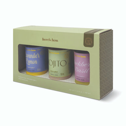 Three small bottles of different flavors in a 'here's how' branded box on a white background