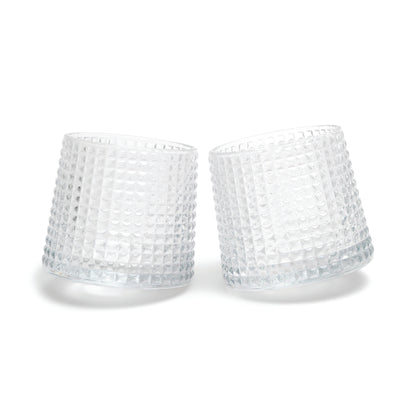 Two of The Lola fluted glasses, featuring a unique spherical bottom design, are displayed tilted towards each other on a white background.