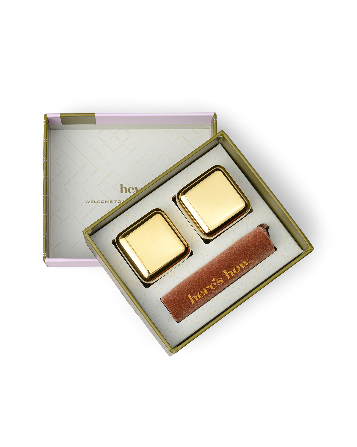The Jupiter: An open gift box contains two gold freezable stainless-steel cubes and a heres how brown item on a white geometric tray—perfect for chilling cocktails without dilution.